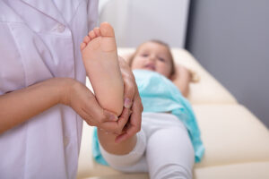 Female pediatric orthopedic surgeon examining young girl's foot in a medical clinic