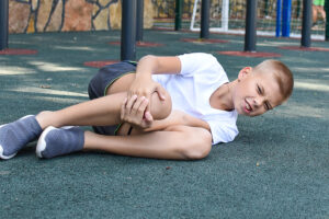 Young boy on a playground clutching his injured knee