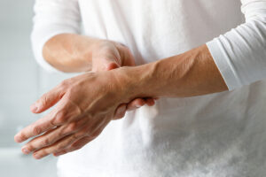 Person in white shirt clutching painful wrist