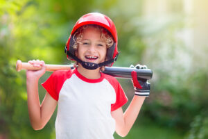 Happy child wearing red helmet and holding baseball bat
