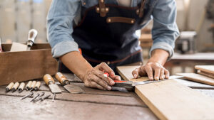Carpenter working with equipment on wooden table in carpentry shop