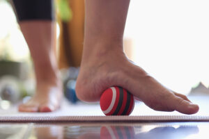 Man using a therapeutic massage ball to work his foot