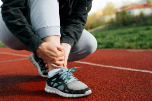 Female runner holding her painful sprained ankle