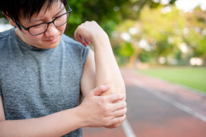 Male runner holding his painful elbow