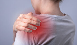 Close-up of woman touching her painful shoulder joint