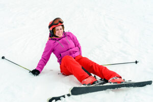 Female skier holding poles after fall on slopes