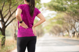 Female runner standing on trail and touching her hip after experiencing snapping hip syndrome
