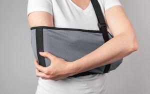 Woman with a radial head fracture touching her painful elbow in a sling